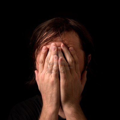 crying-man-with-hands-covering-his-face-in-low-light-interior